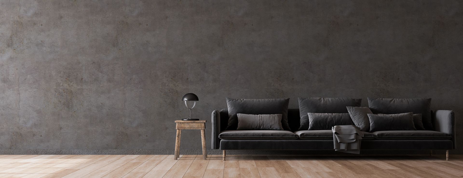 Soggiorno minimalista con divano nero, tavolino e parete grigia con texture.