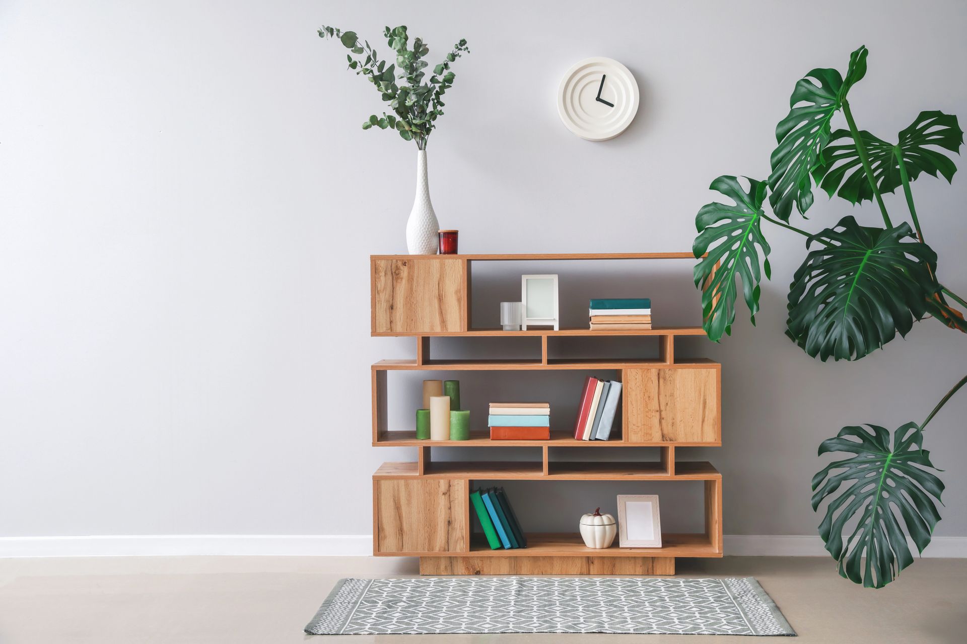 Soggiorno moderno con mensola in legno, piante verdi, orologio da parete e tappeto a motivi geometrici.