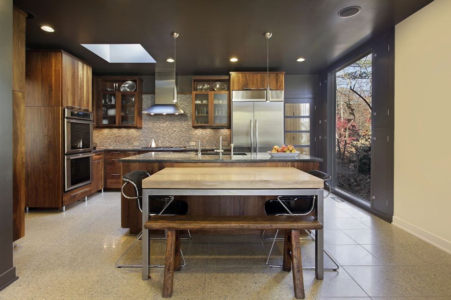 Cucina moderna con isola, mobili in legno scuro, paraschizzi piastrellato e ampia finestra.