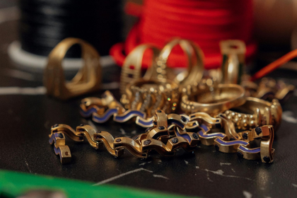 Assorted gold and silver metal bracelets and bangles displayed on a dark surface