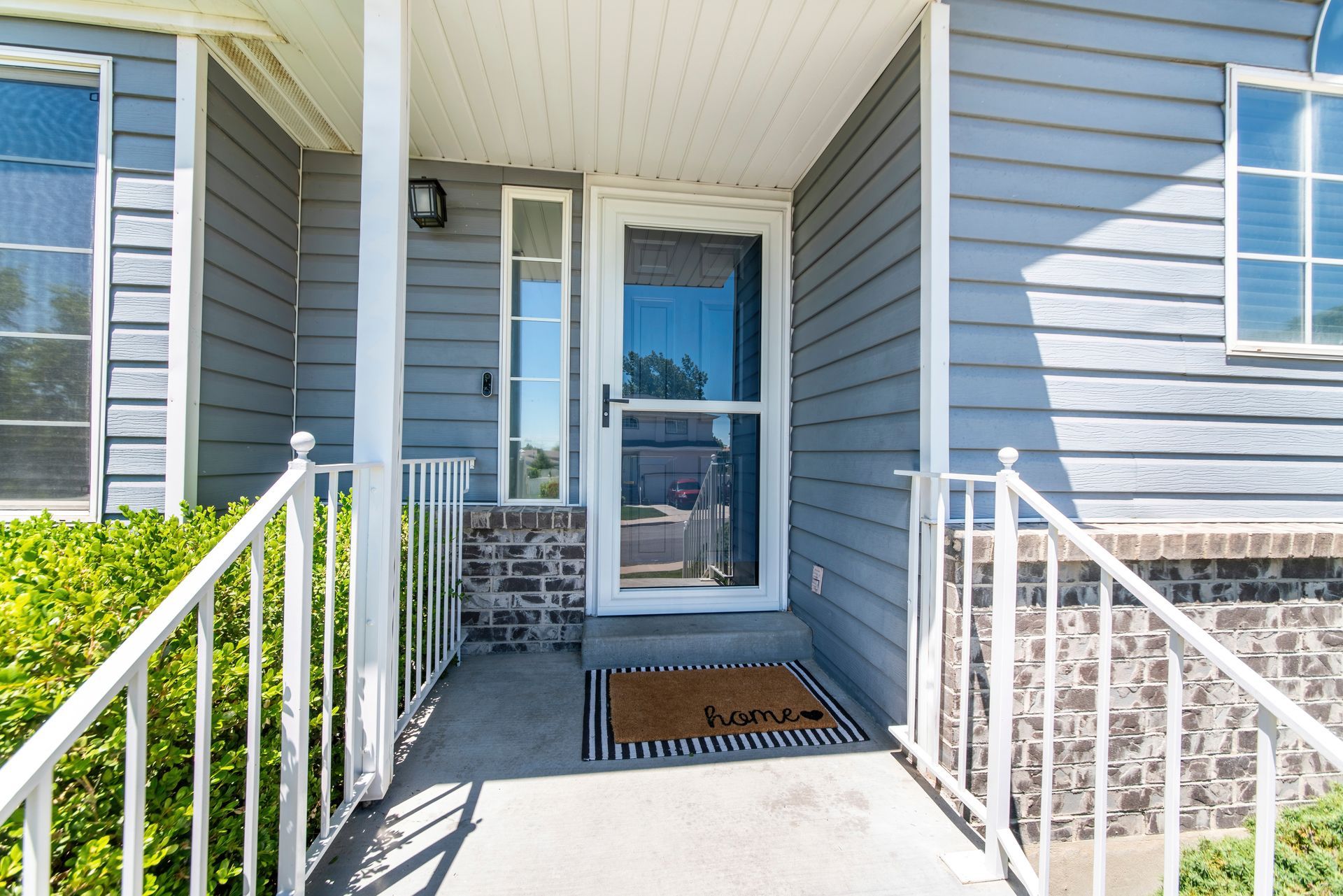 Blue house entrance with white railings, a doormat that reads 