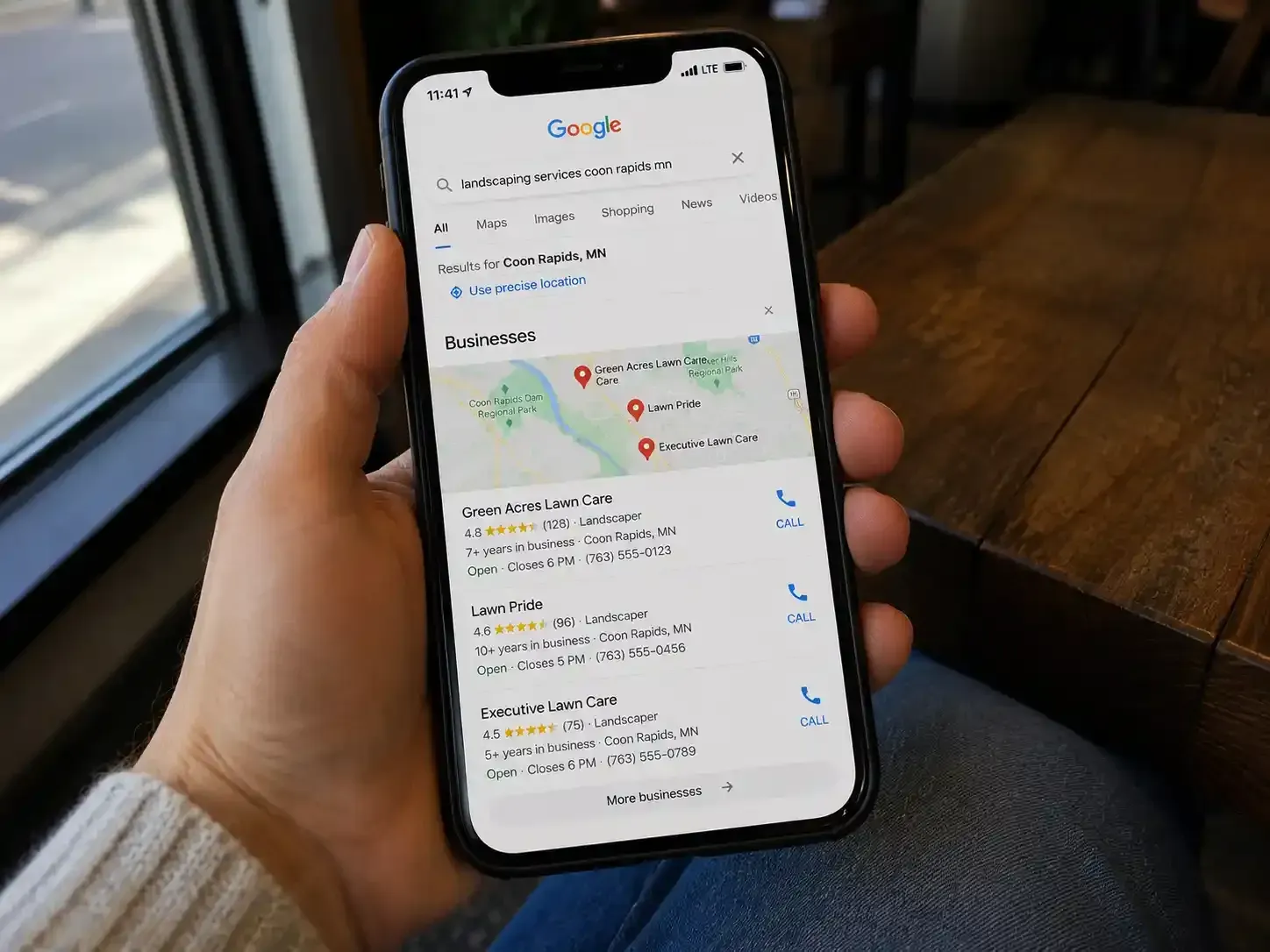 Hand holding smartphone showing Google Maps directions and local search results on a car ride