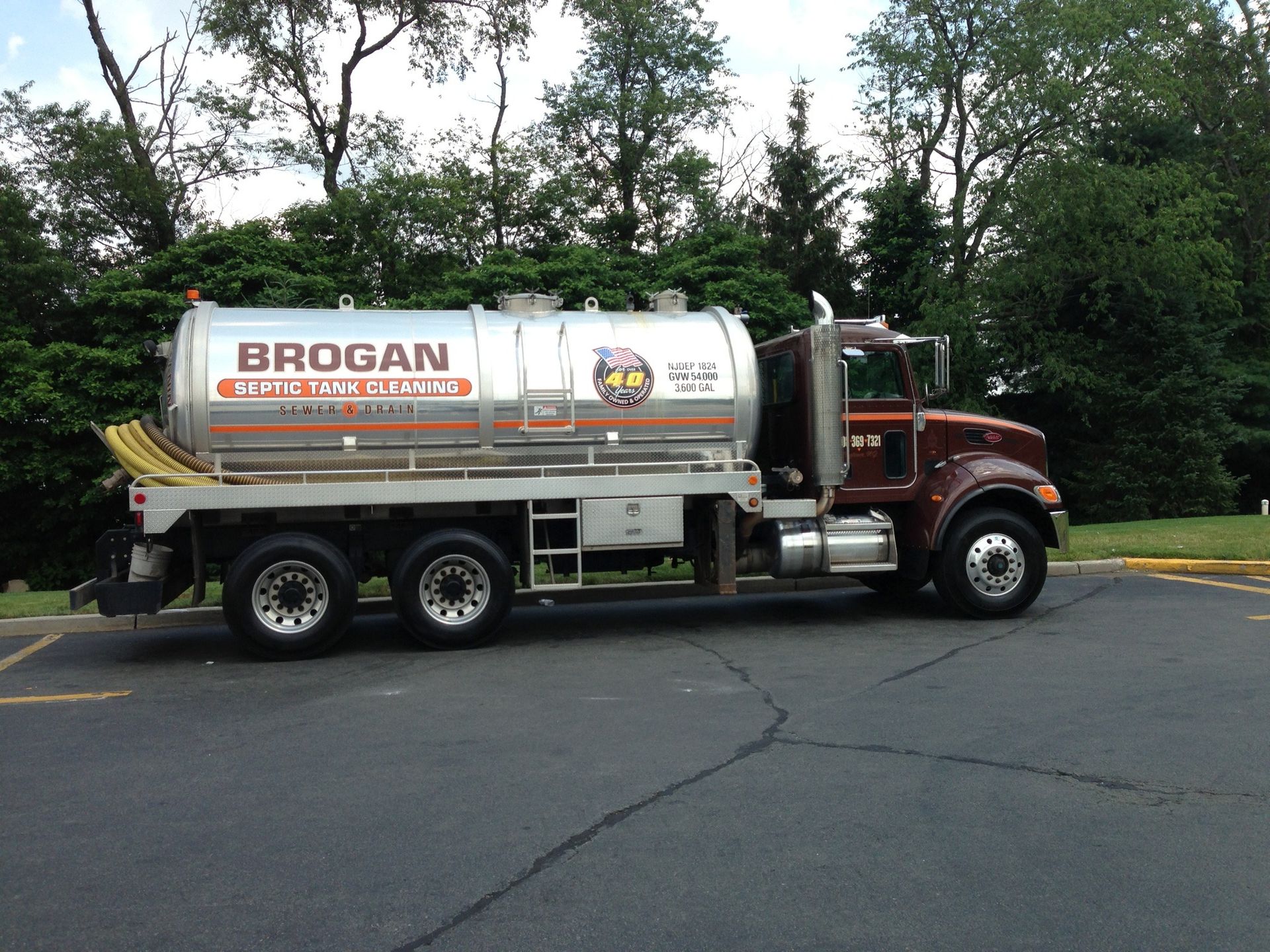 White Brogan tanker truck parked on a road beside trees and grass