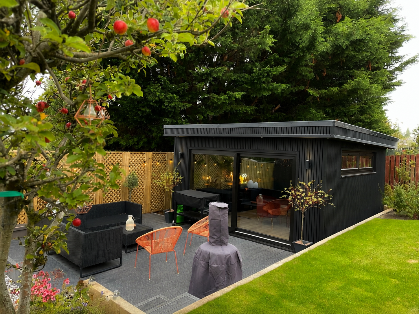Completed Oakspan garden room with contemporary black cladding, glazed doors and landscaped garden