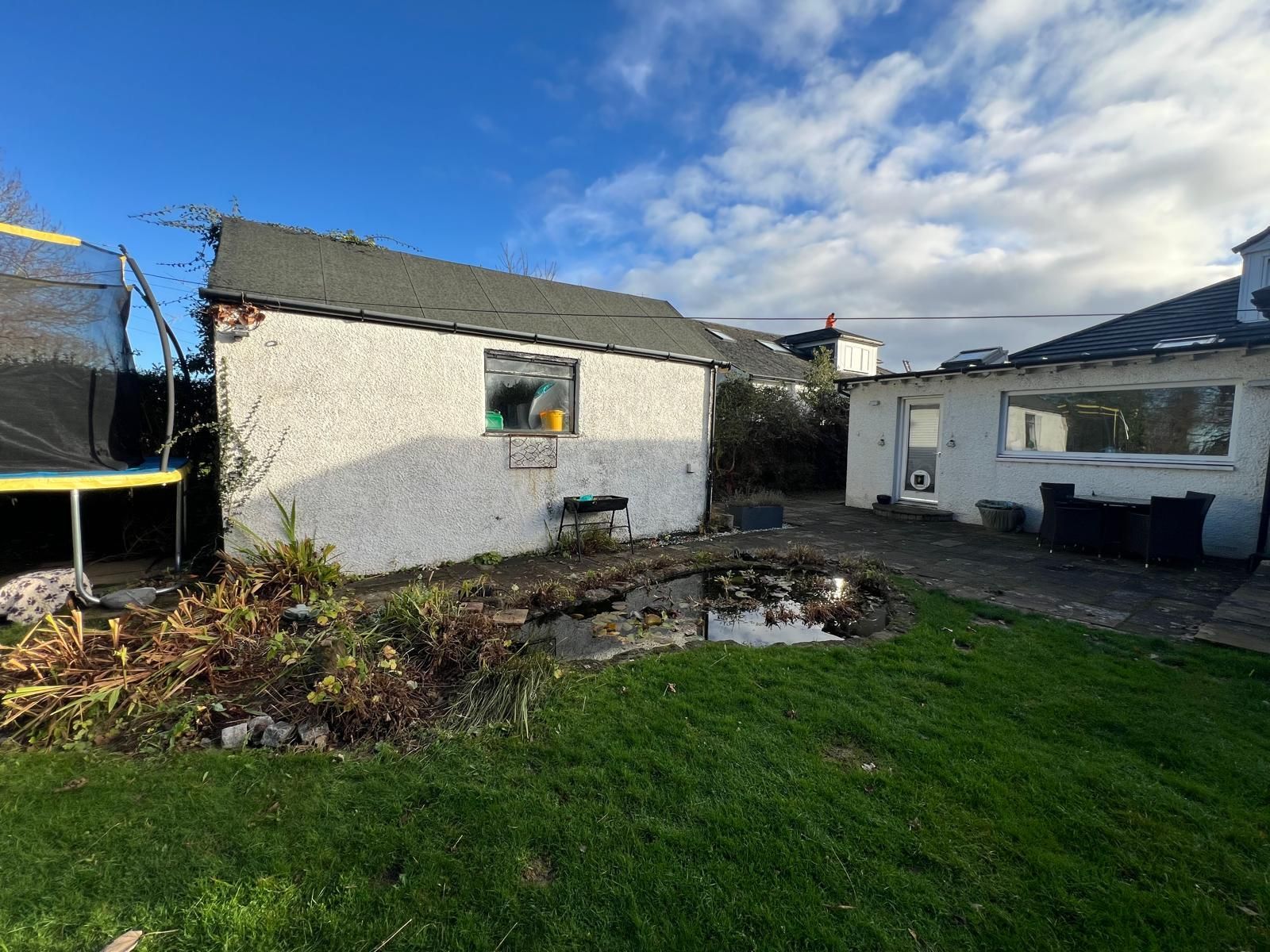 Garden and existing garage before Oakspan pitched roof garden room construction in Newton Mearns