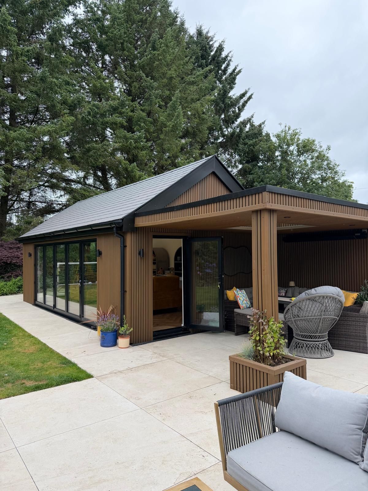 Oakspan pitched roof garden room in Newton Mearns with glazed doors, composite cladding and covered outdoor canopy