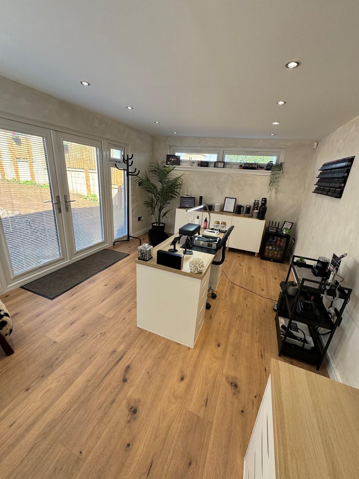 Interior of a purpose-built salon garden room featuring black sockets and switches, full electrics, internet connection, and a clean, modern aesthetic.