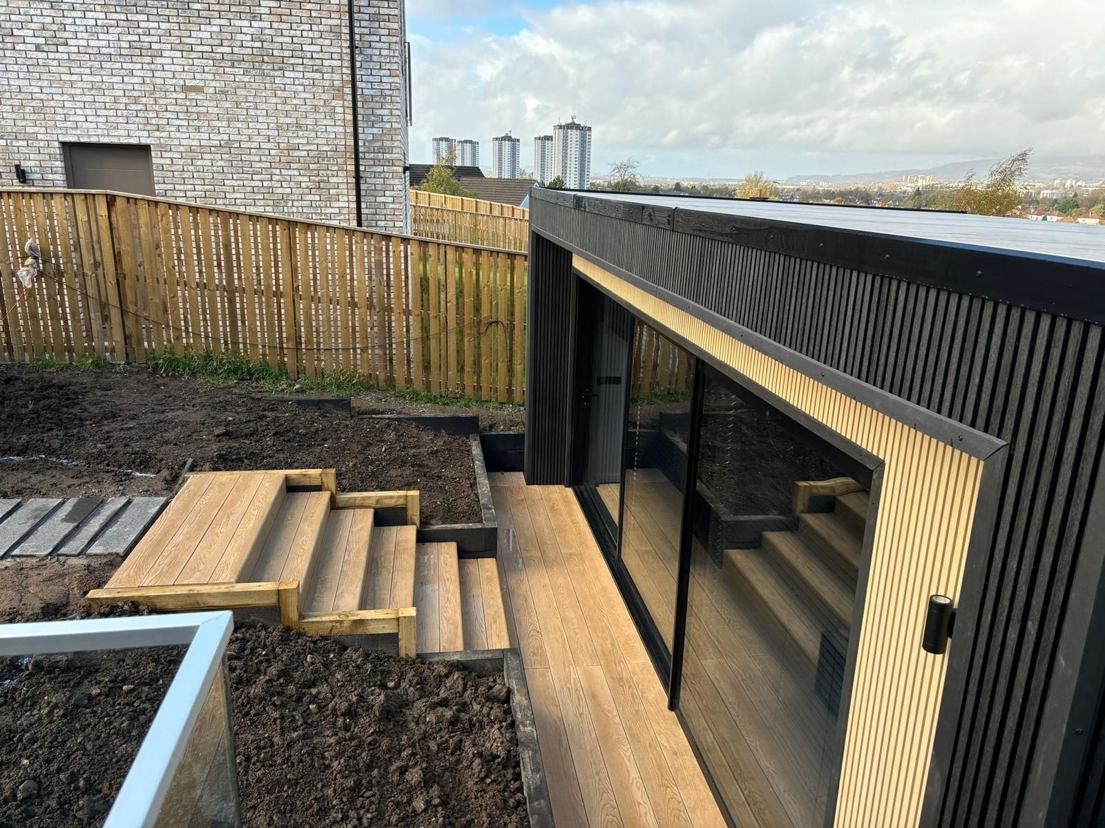 Finished Oakspan golf simulator garden room exterior with premium cladding and landscaped garden
