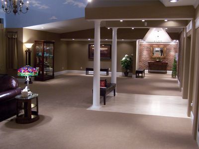Spacious, carpeted lobby with neutral walls, white support columns, a Tiffany-style lamp, and a brick-accented entryway.