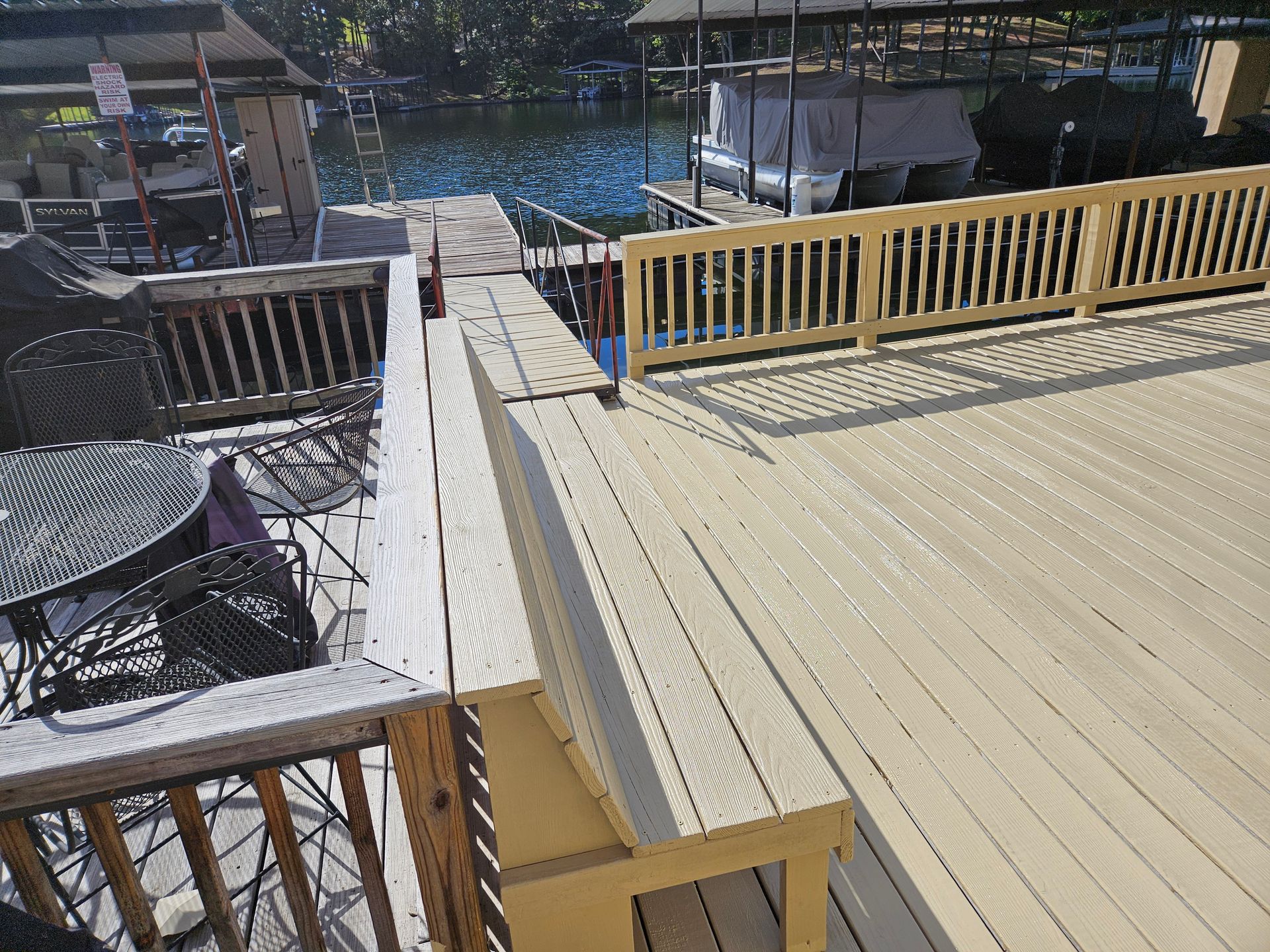 Wooden deck with yellow railing beside a marina and boats on calm water