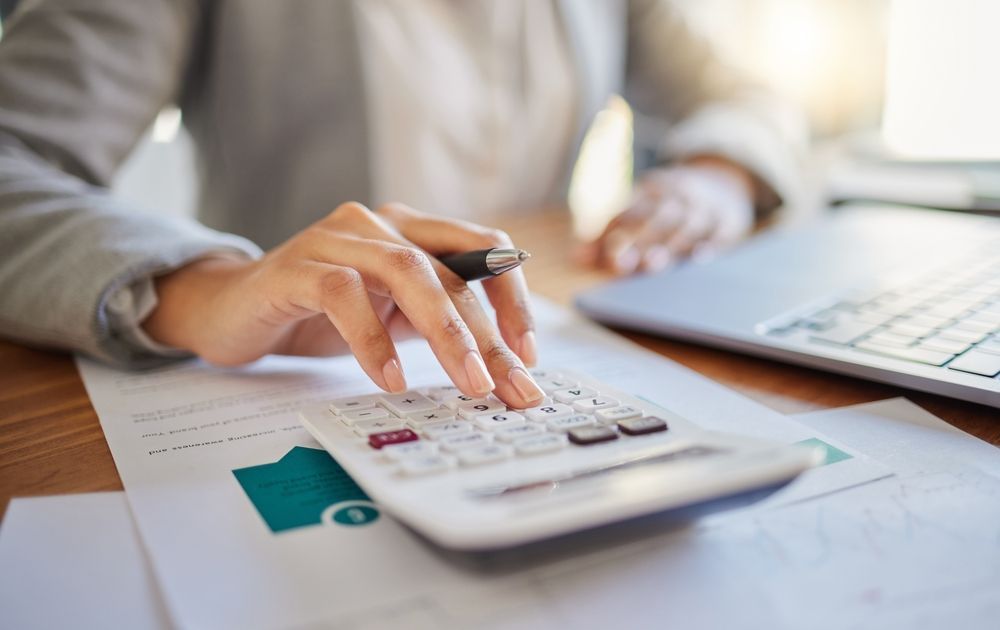 A fractional CFO is using a calculator and a pen at a desk gathering expert data