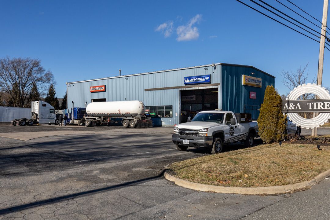 Industrial building with blue siding, parked truck and tanker trailer, under a clear sky.