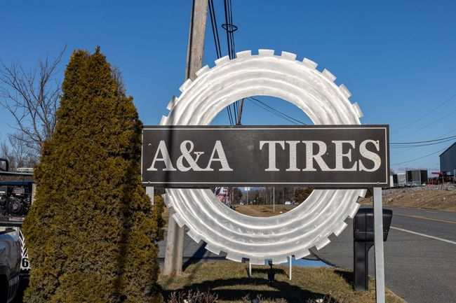 A&A Tires sign with a large white tire sculpture beside a roadside on a sunny day