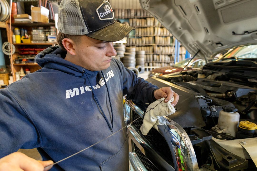 Mechanic in blue hoodie inspecting engine in a garage with hood open
