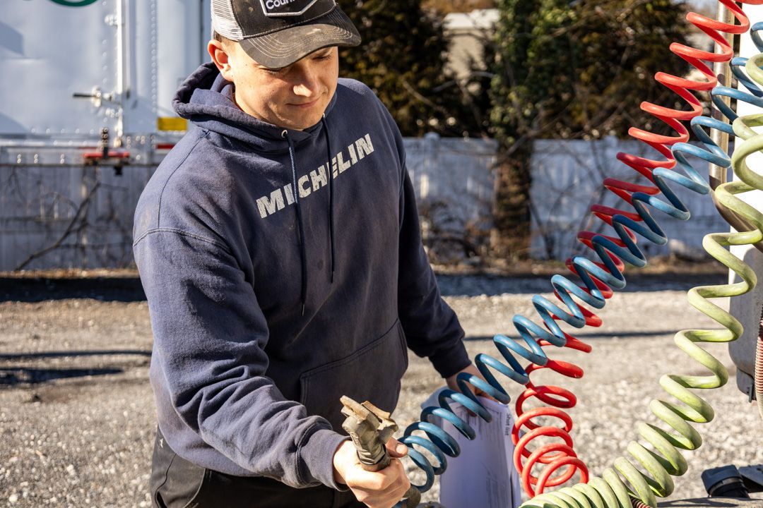 Worker in a navy sweatshirt handling coiled hoses outdoors