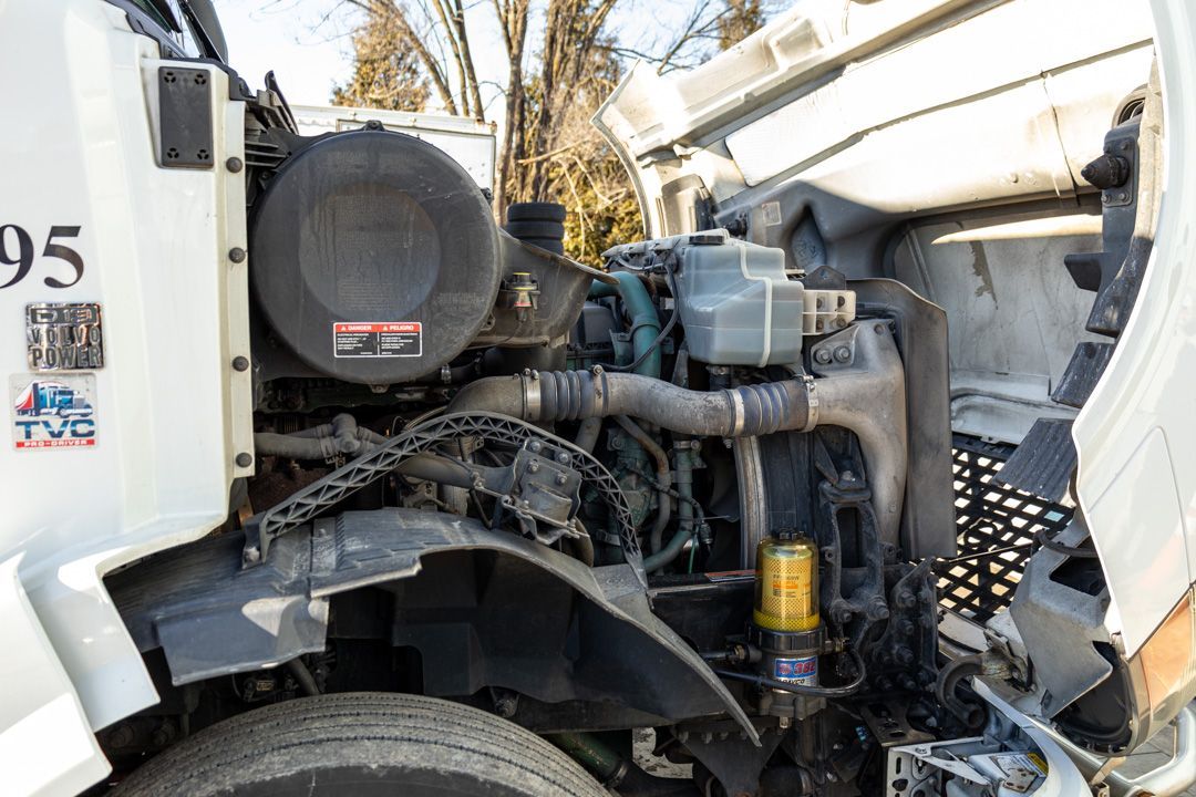 Damaged white truck cab with exposed engine and front-end components after a collision