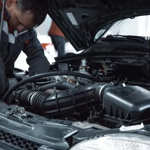 Mechanic inspecting an open car engine bay with the hood raised