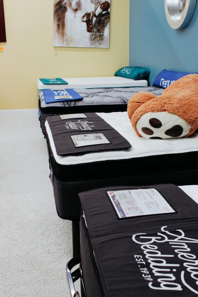 Rows of folded blankets on a bed in a room, with a plush panda and orange pillow on top