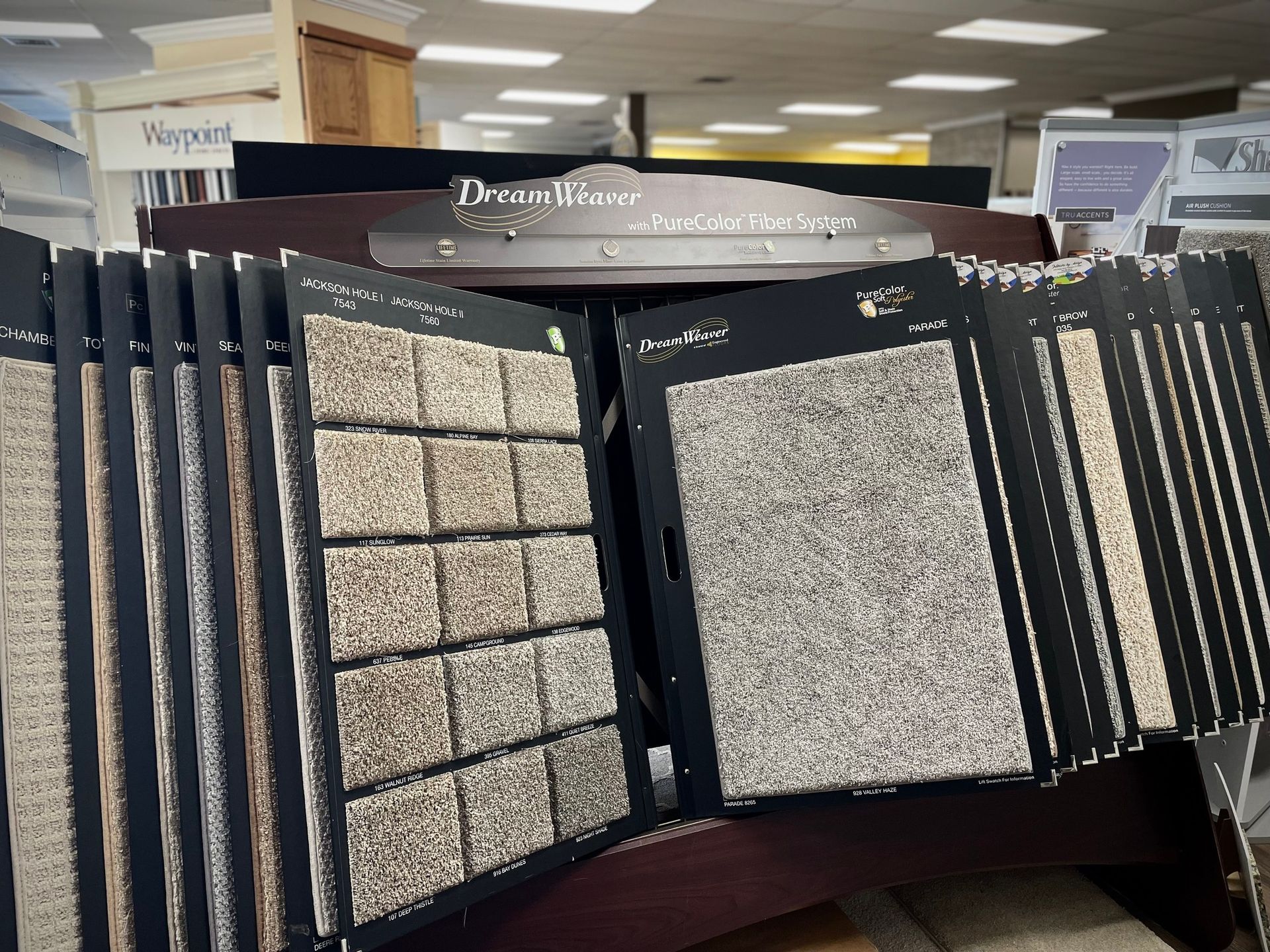 Display rack of exterior siding samples in a showroom, showing stone, brick, and gray textured panels.