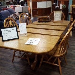 Wooden dining table with chairs in a showroom, with signs and brochures on top
