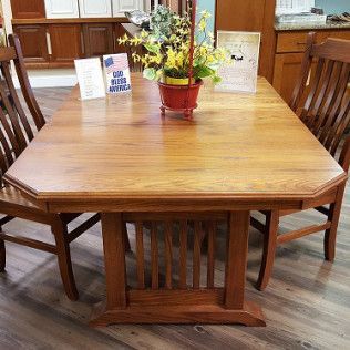 Wooden dining table and chairs with a flower centerpiece in a showroom