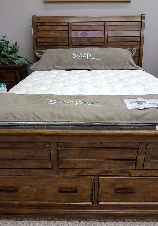 Wooden bed frame with beige bedding and matching headboard and footboard in a bedroom
