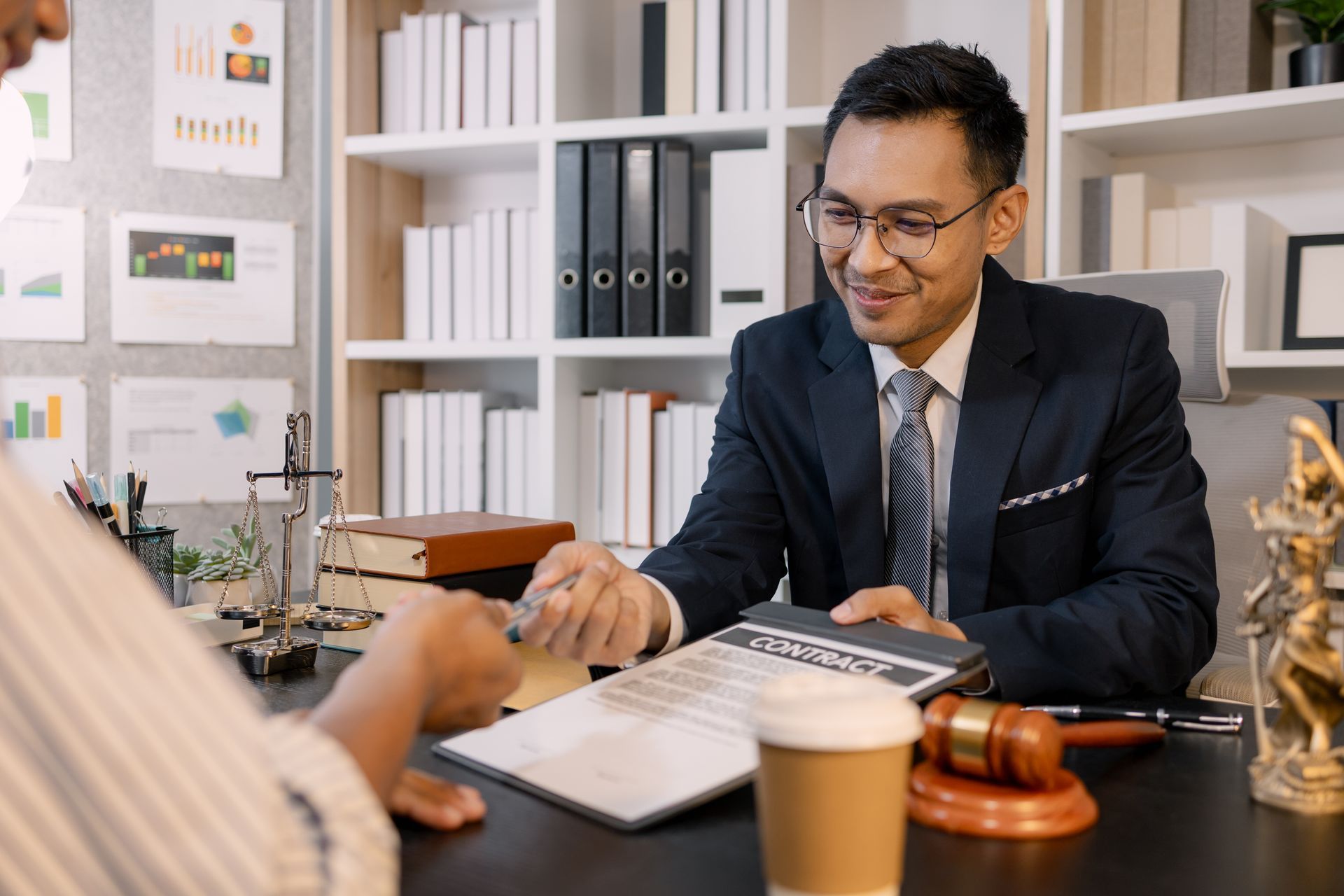 Attorney reviewing documents with a client across a desk in an office, with a gavel and coffee cup nearby