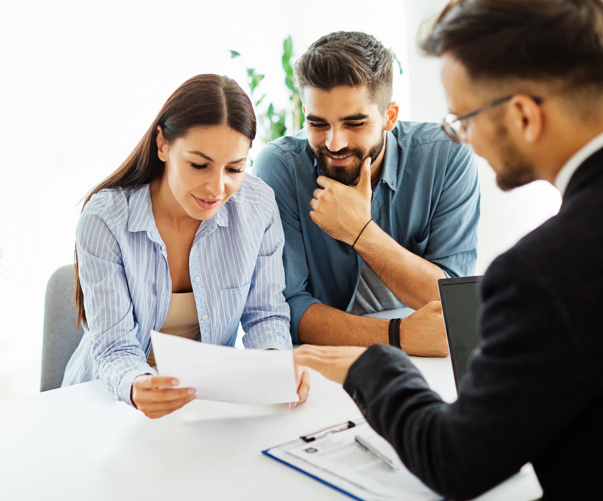 Three people reviewing a document together at a desk in a bright office