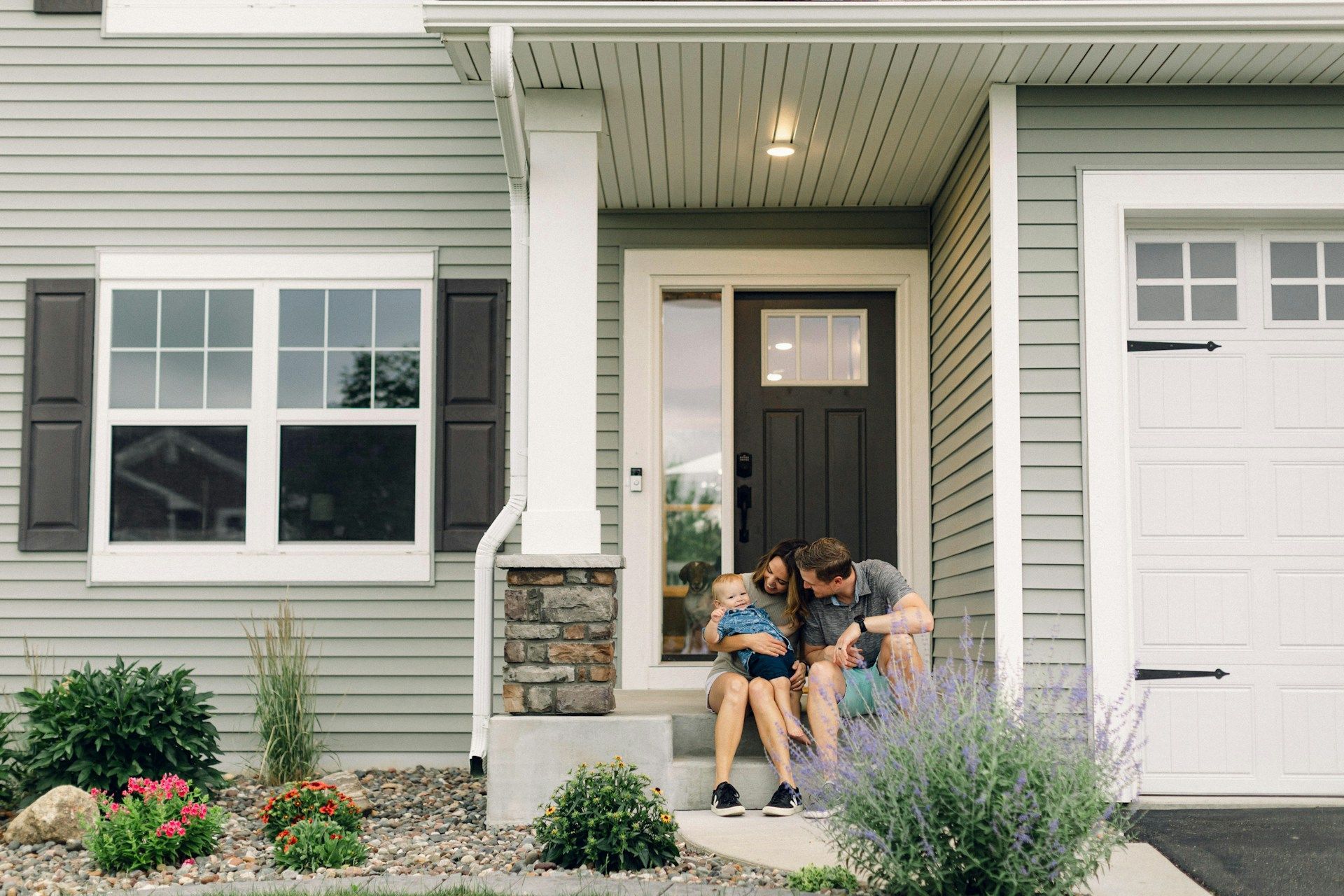 Two people sitting on front steps of a house, leaning together by the doorway