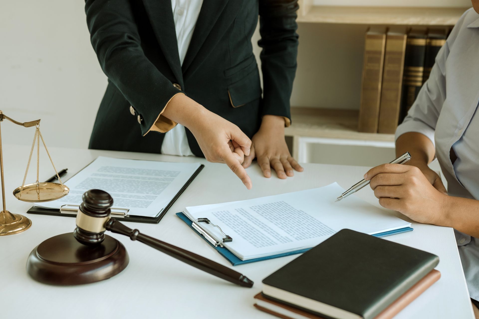 Lawyer points to documents during a meeting beside a gavel and scales of justice