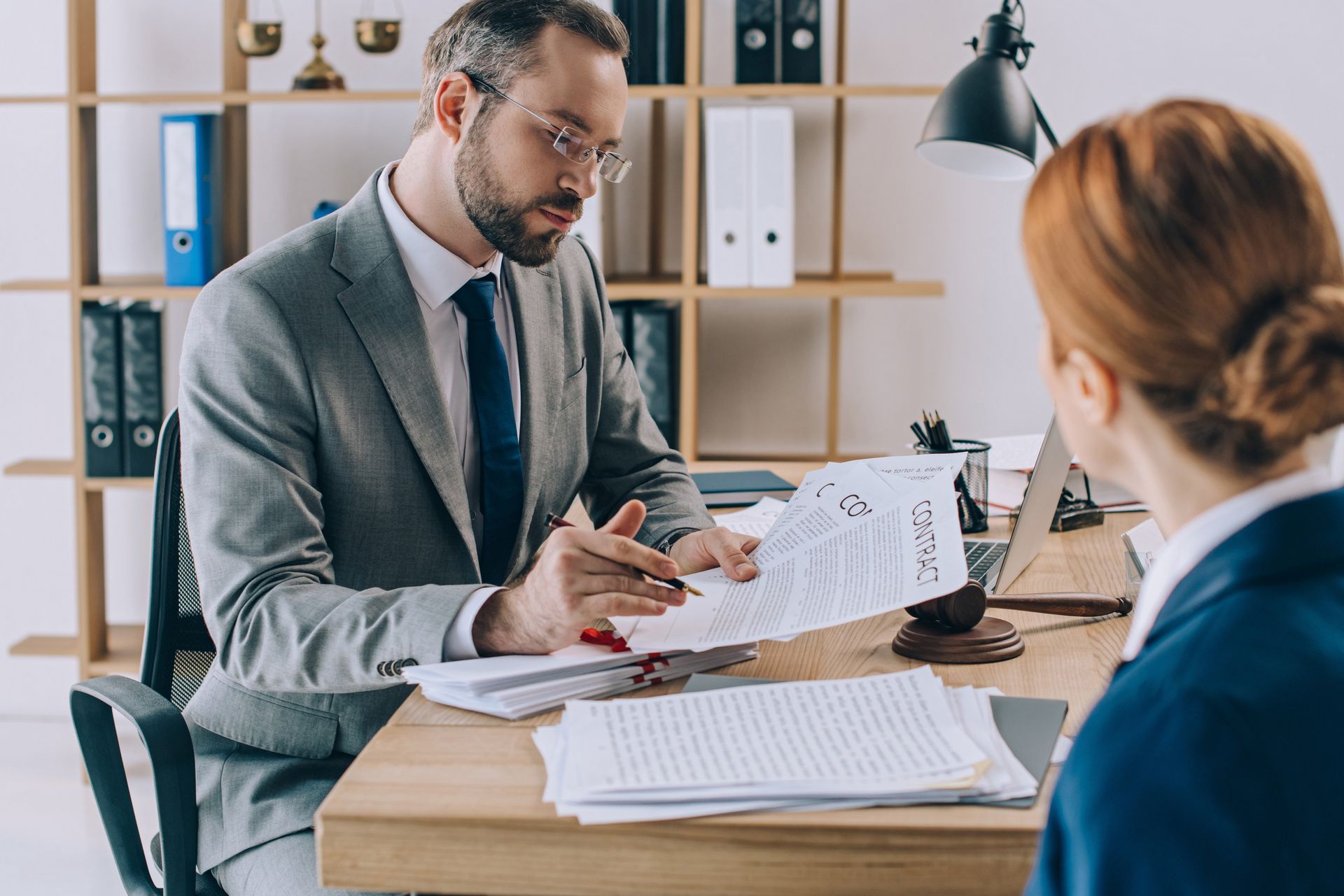 Two coworkers reviewing documents during a meeting at a desk in a bright office