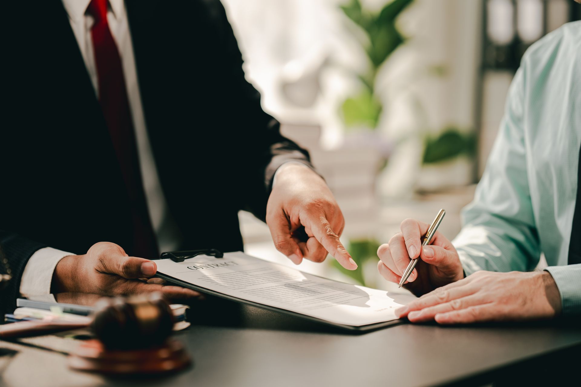 Hands signing a legal document at a desk beside a gavel