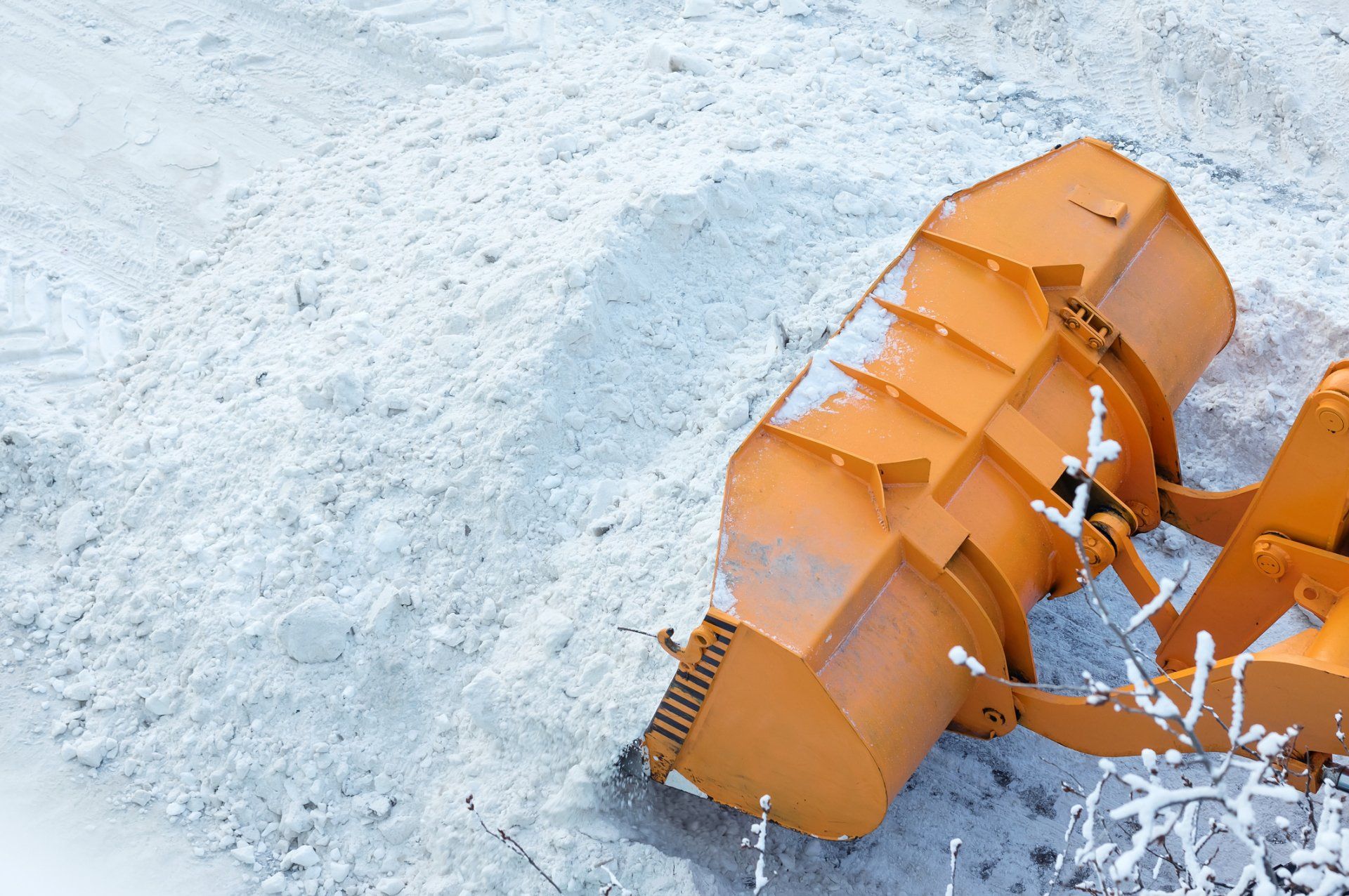 a snow plow is sitting in the snow on the side of the road .