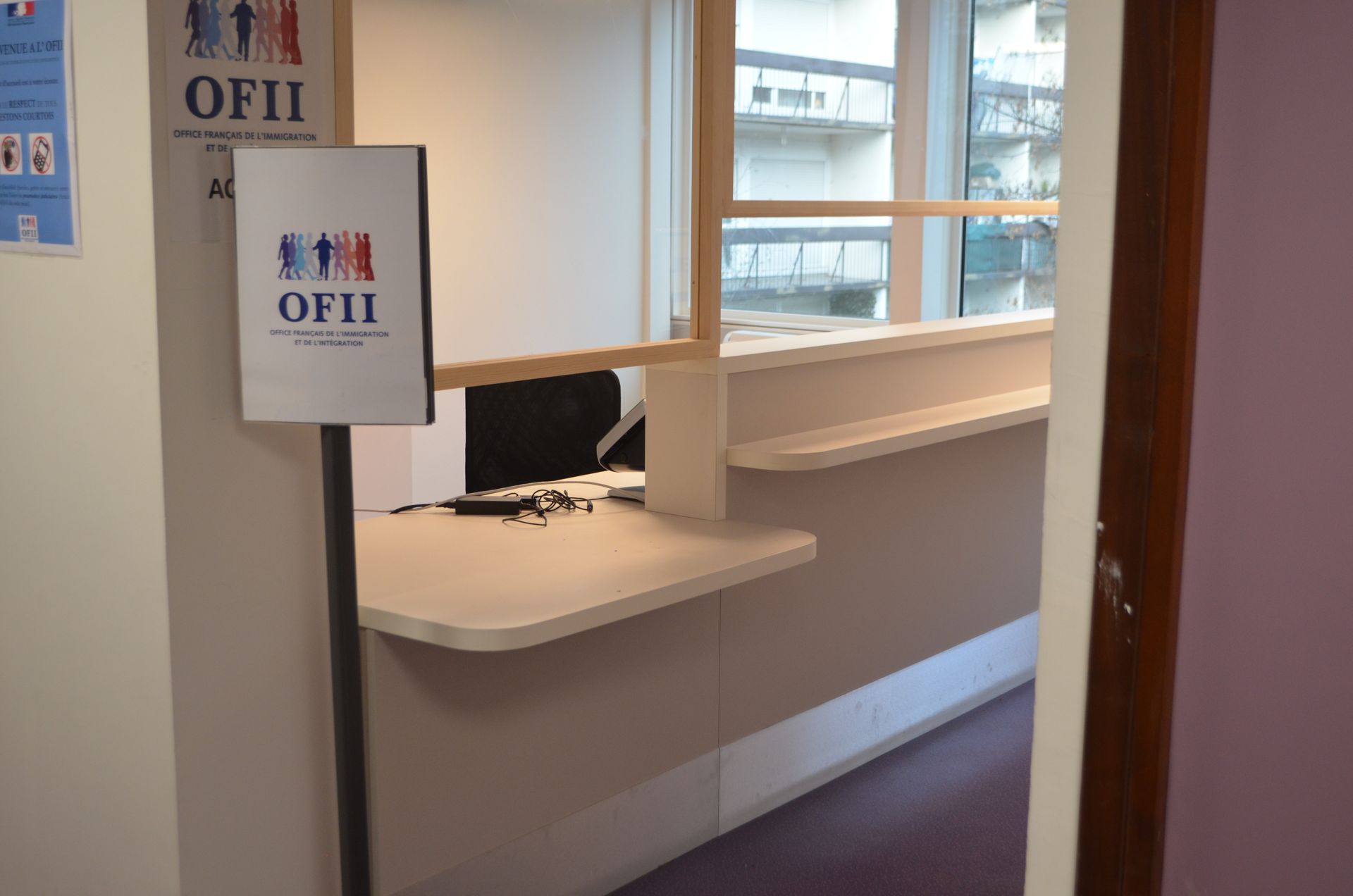 Un comptoir d'accueil portant l'inscription OFII dans un environnement de bureaux lumineux.