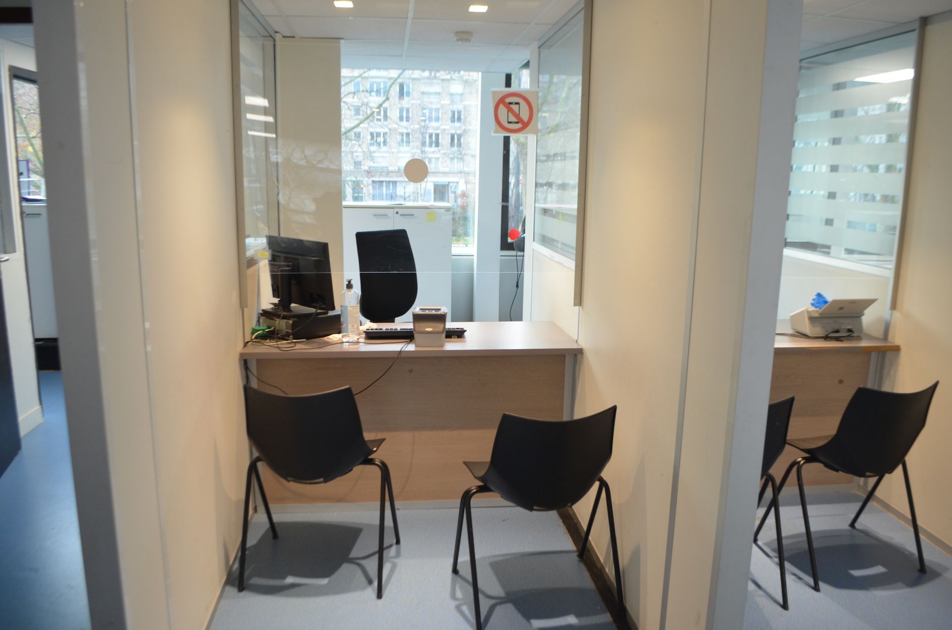 Un espace de bureau professionnel avec deux cabines de service, chacune équipée d'un bureau, d'un ordinateur et de deux chaises noires.