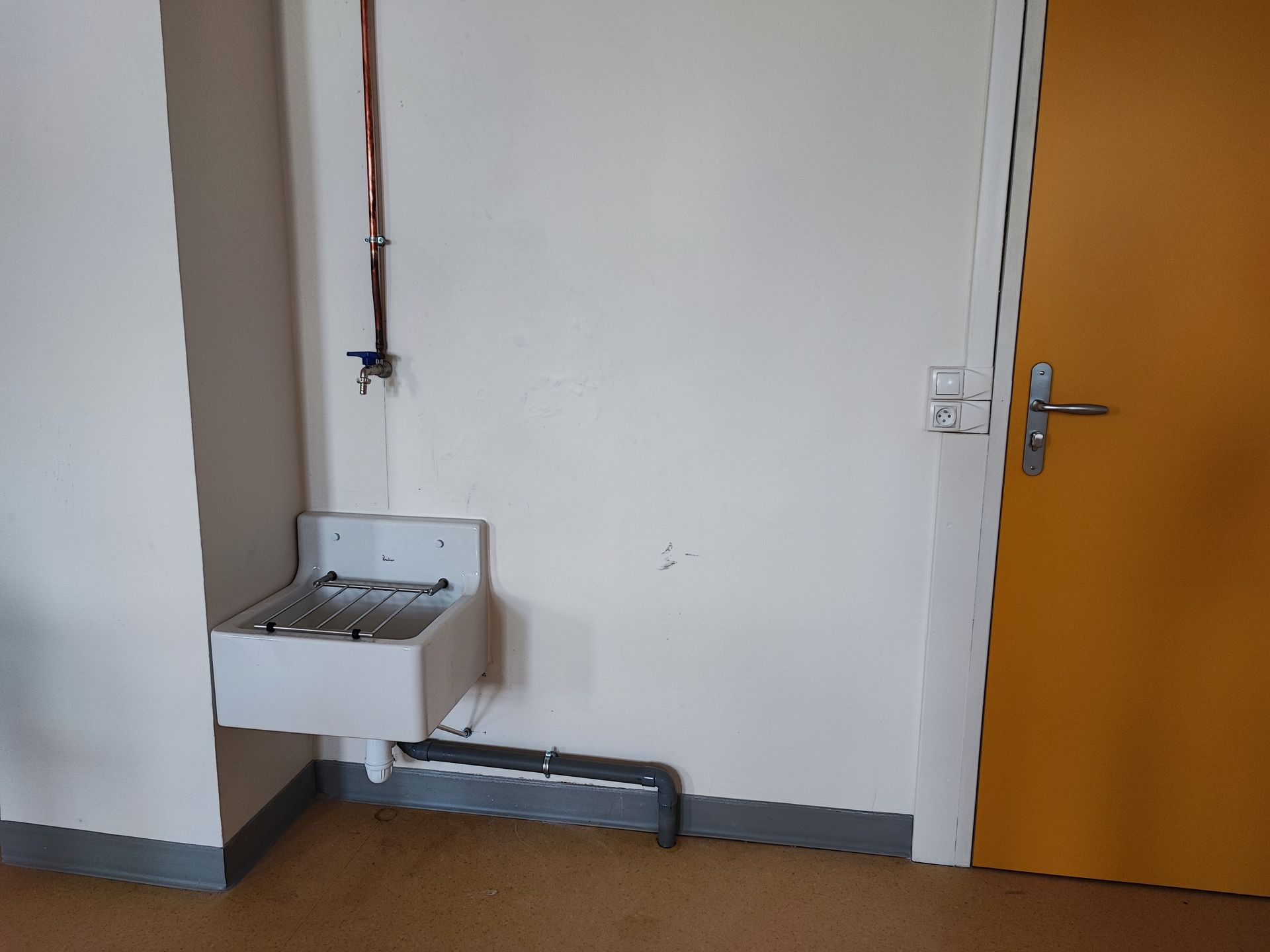 Une salle de classe lumineuse avec plusieurs planches à repasser alignées près de grandes fenêtres et une grande table sur la droite.