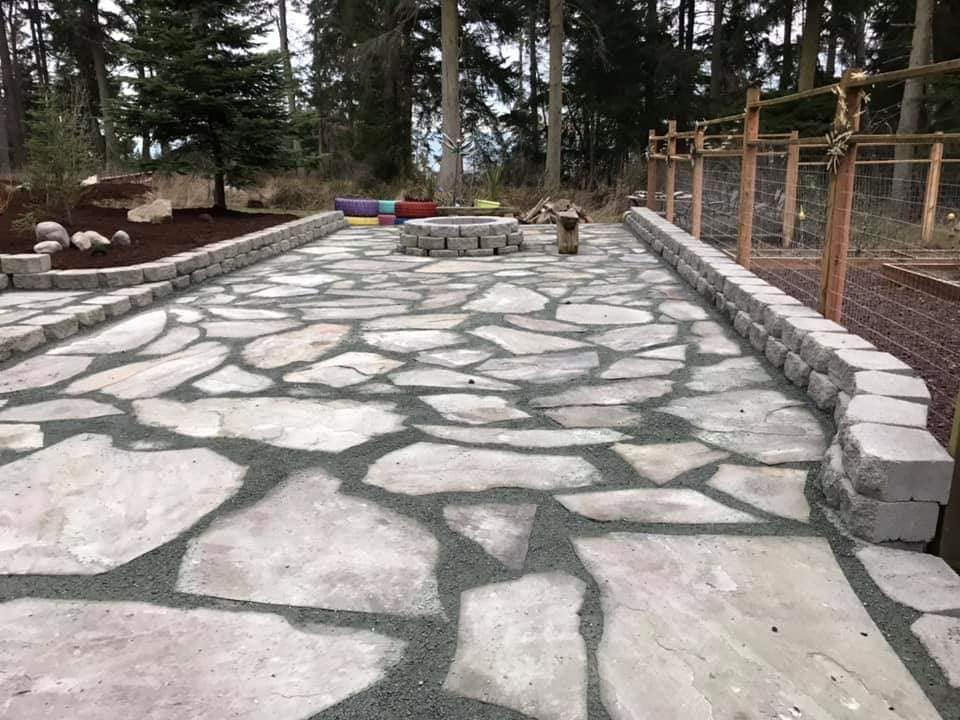 Stone patio with a fire pit surrounded by a low retaining wall.