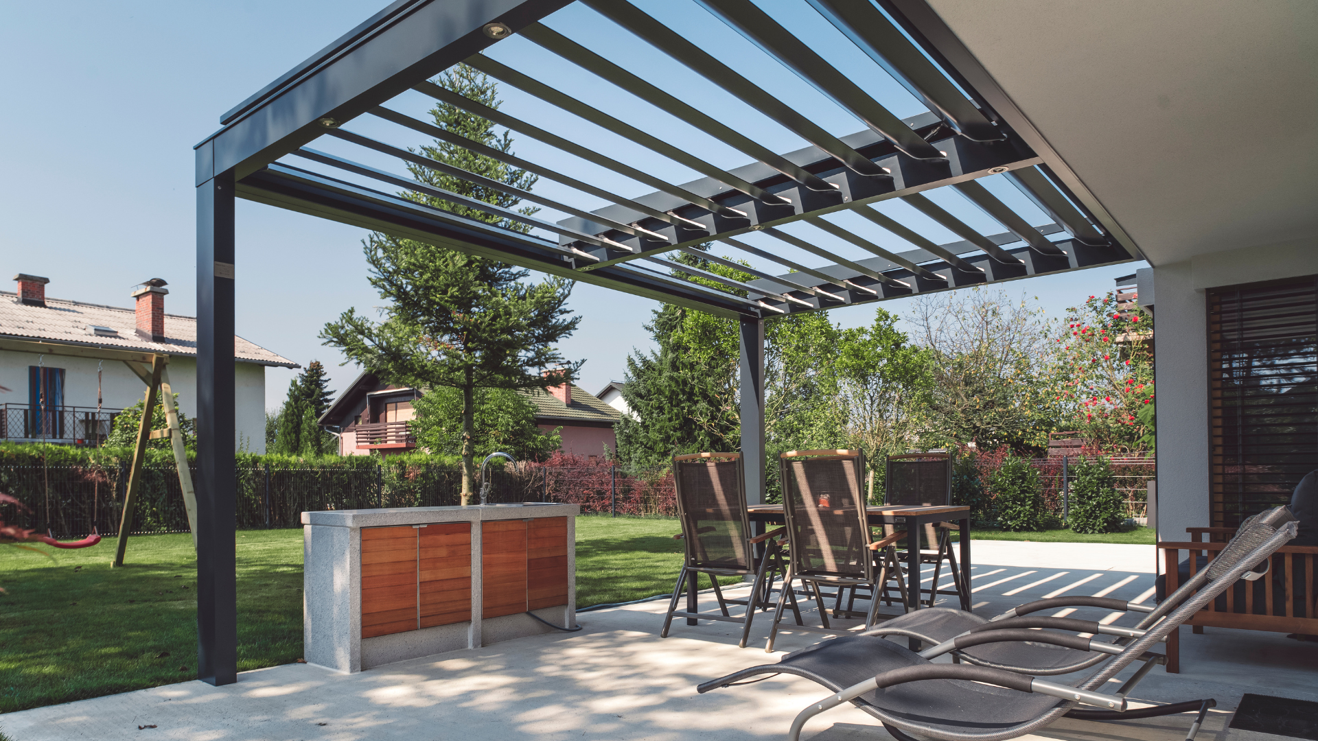 Patio with metal pergola, outdoor seating, and a built-in wooden grill.