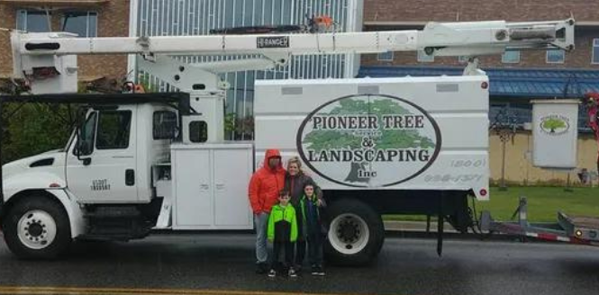 Family posing in front of a white truck with a lift, advertising