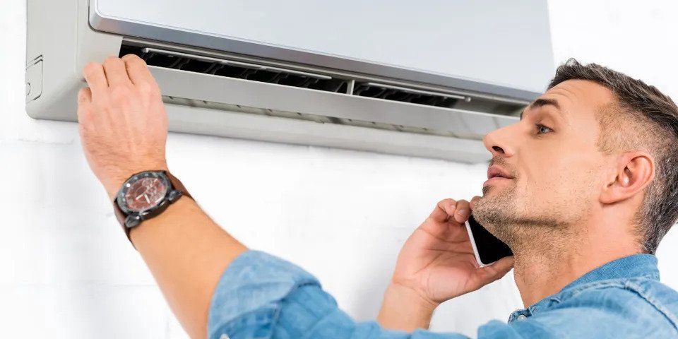 Man Talking on Phone While Standing Near Air Conditioner — Nicholasville, KY — Stewart Air Conditioning & Heating Man Talking on Phone While Standing Near Air Conditioner — Nicholasville, KY — Stewart Air Conditioning & Heating
