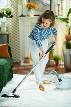 Woman Vacuuming White Fluffy Carpet — Nicholasville, KY — Stewart Air Conditioning & Heating Woman Vacuuming White Fluffy Carpet — Nicholasville, KY — Stewart Air Conditioning & Heating