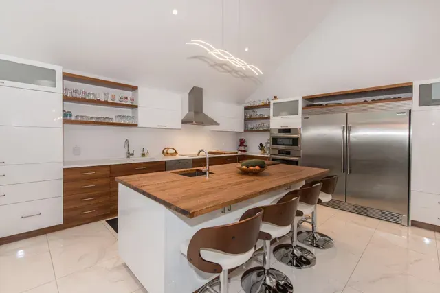 une cuisine avec électroménagers en acier inoxydable, armoires en bois et un grand îlot.