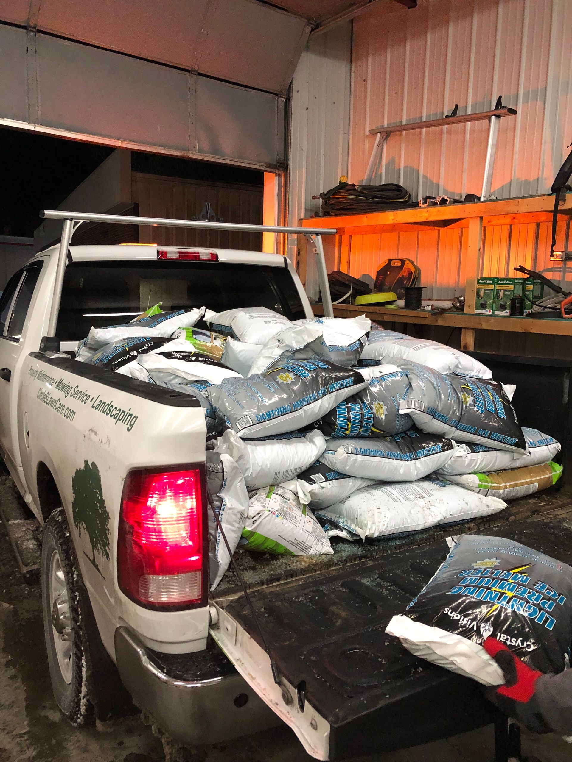 Pickup truck bed piled high with bags of material in a warehouse bay, rear tailgate open