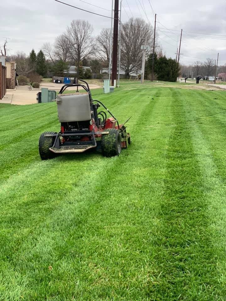 Zero-turn mower mowing a green lawn on an overcast day