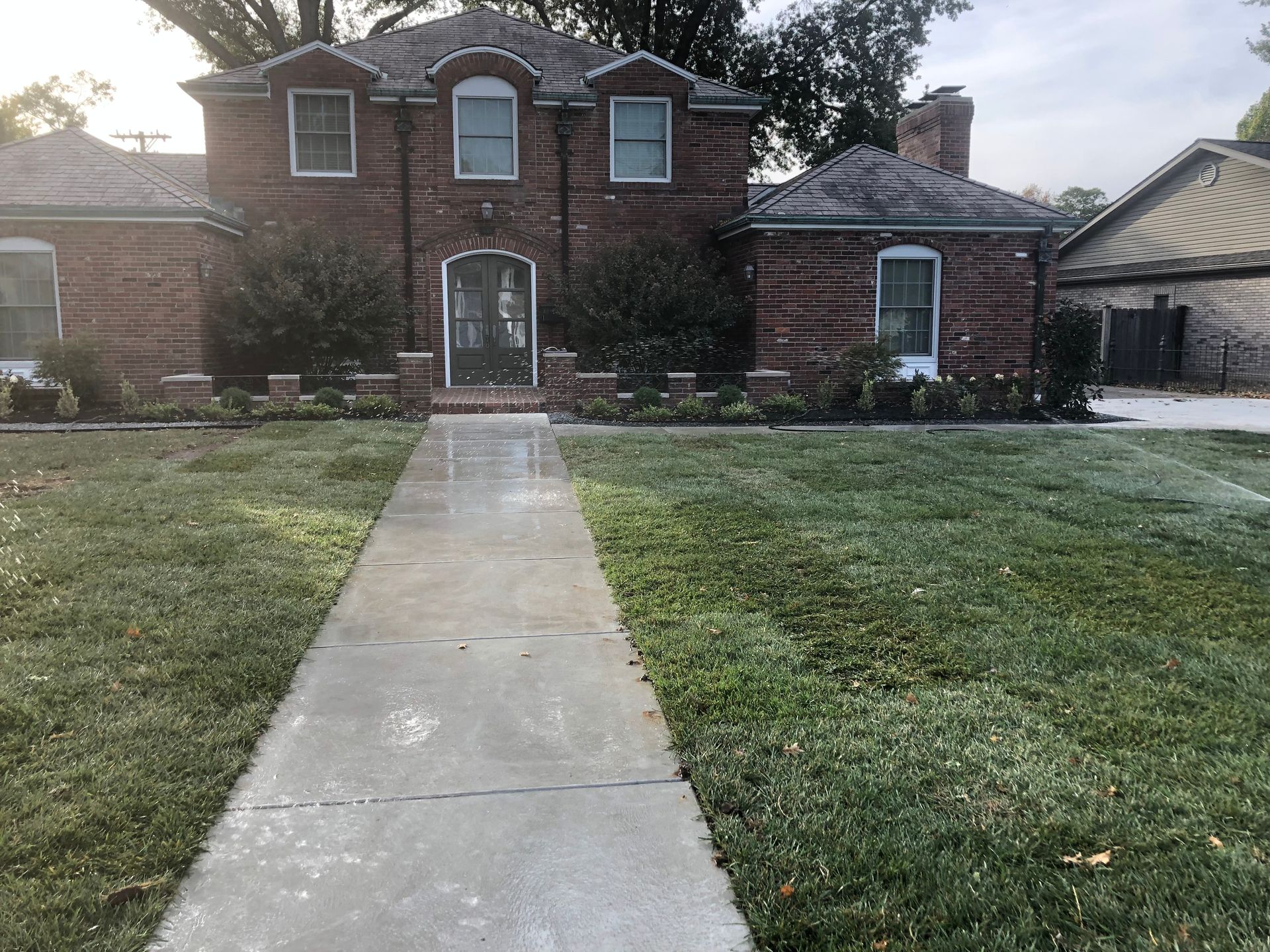 Brick house with a front walkway and lawn under a cloudy sky