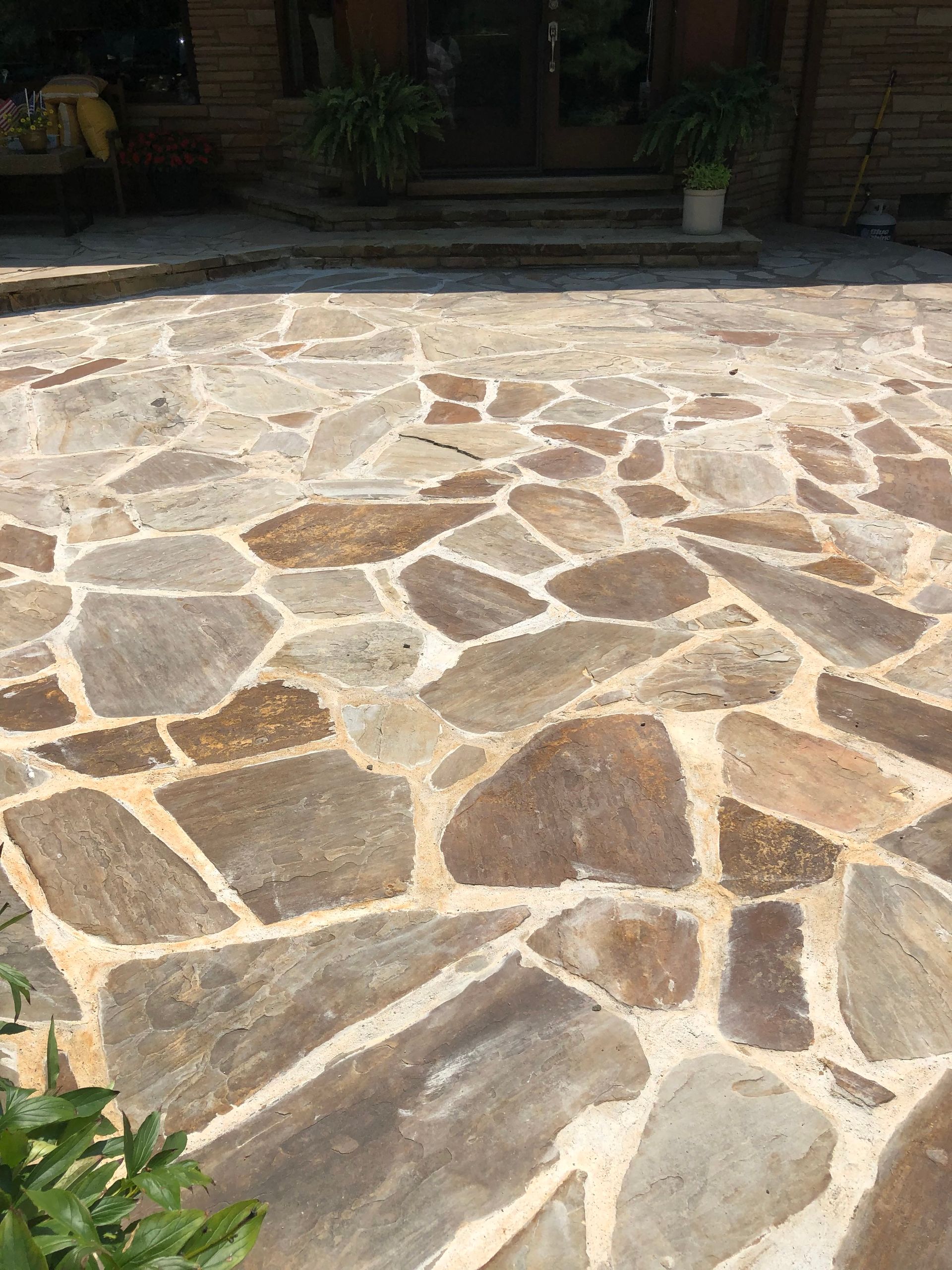 Stone-paved patio with irregular tan and gray flagstones in sunlight