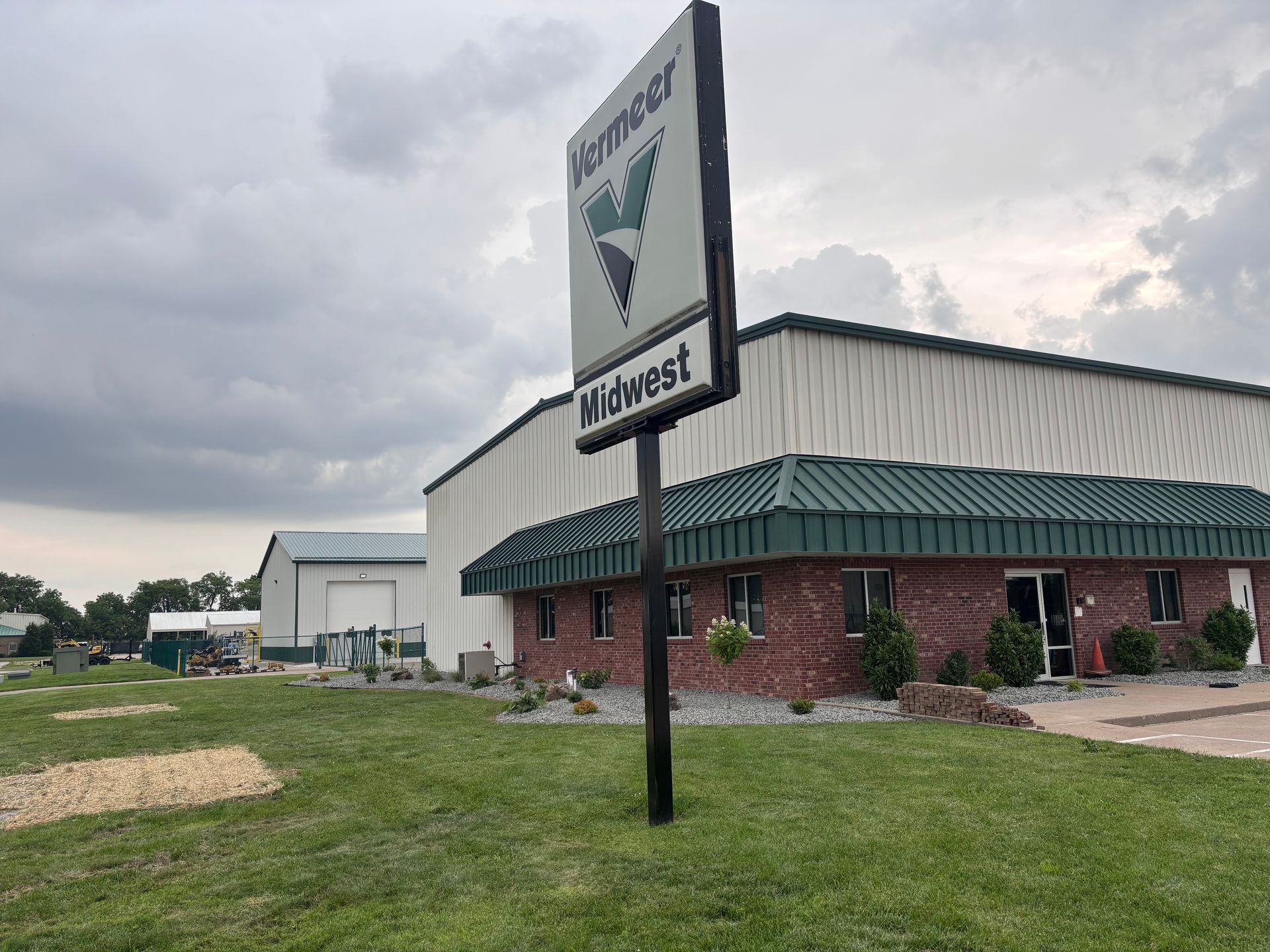 Midwest building with a green roof and brick exterior under a cloudy sky, seen from a grassy lot