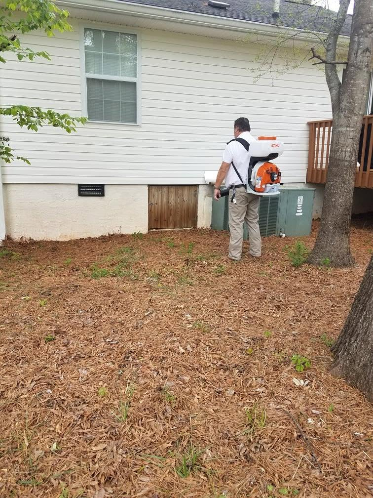 Man standing on a wooden deck beside a white house, inspecting an electrical meter and panel.