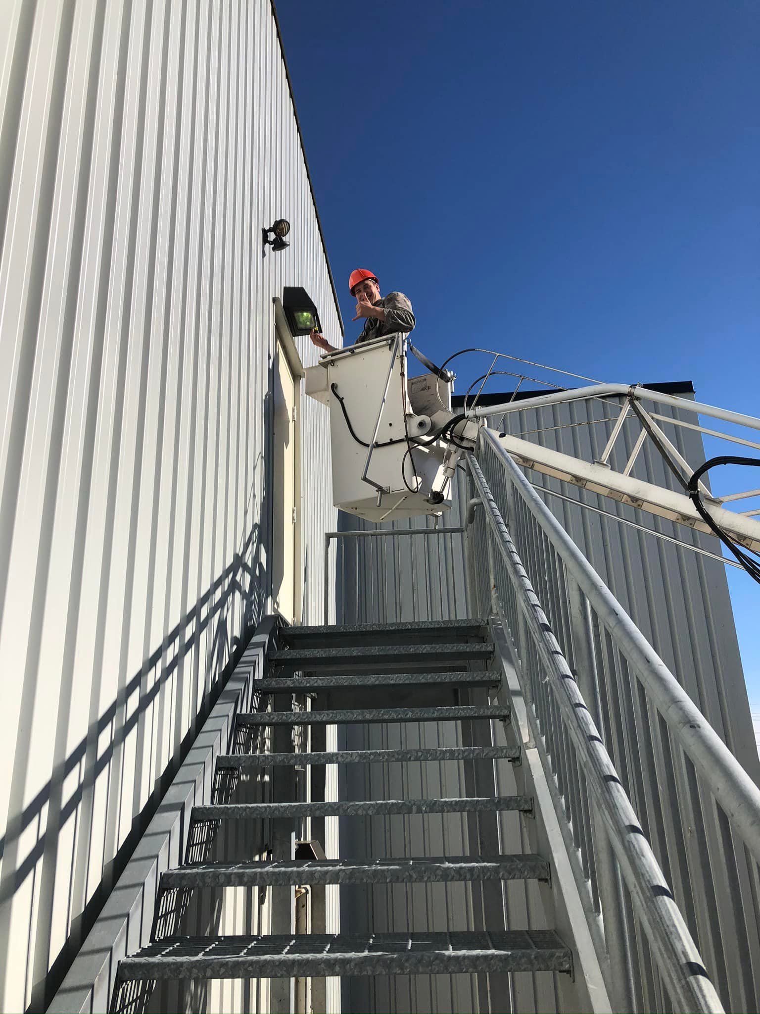 A man is standing in a bucket on top of a set of stairs.