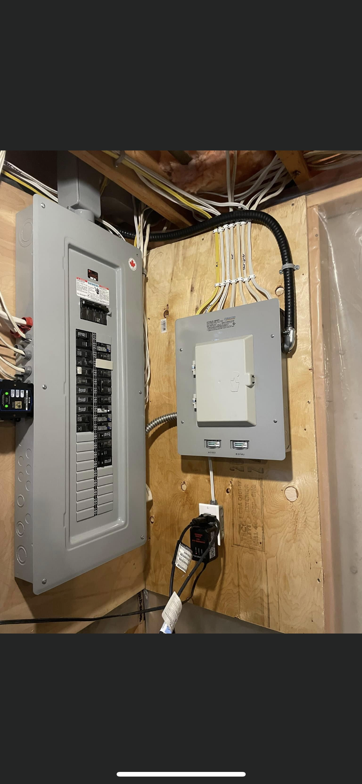 A electrical box is hanging on a wall in a basement.